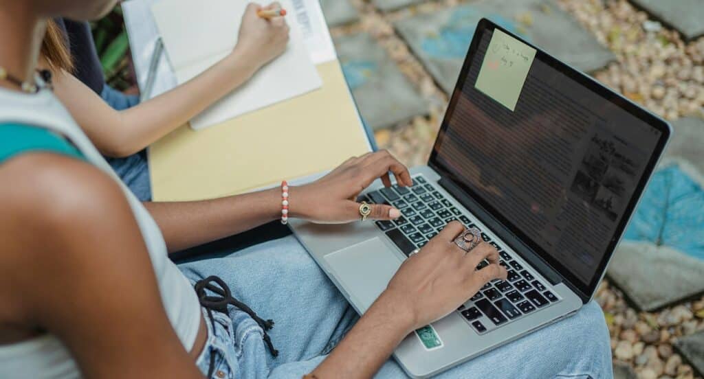 A woman's hands rest on the keyboard of an open laptop.