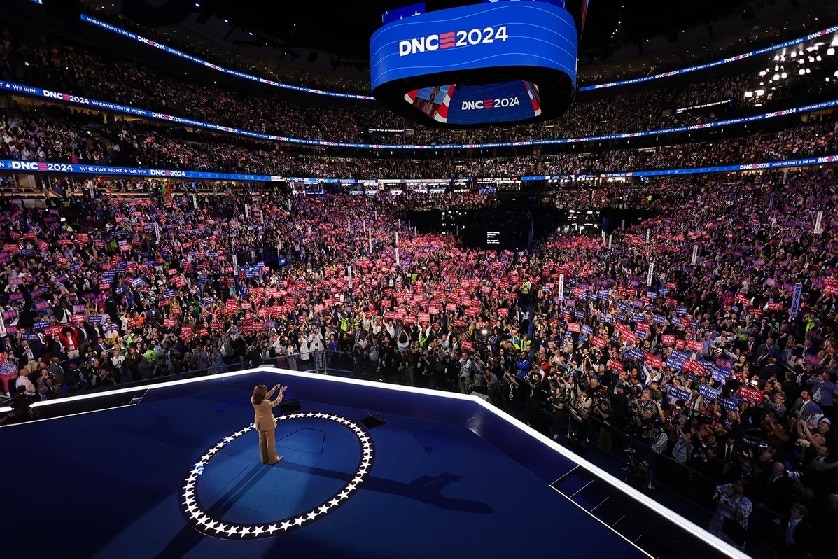 Kamala Harris stands at center stage, greeting the audience, during the 2024 Democratic National Covention