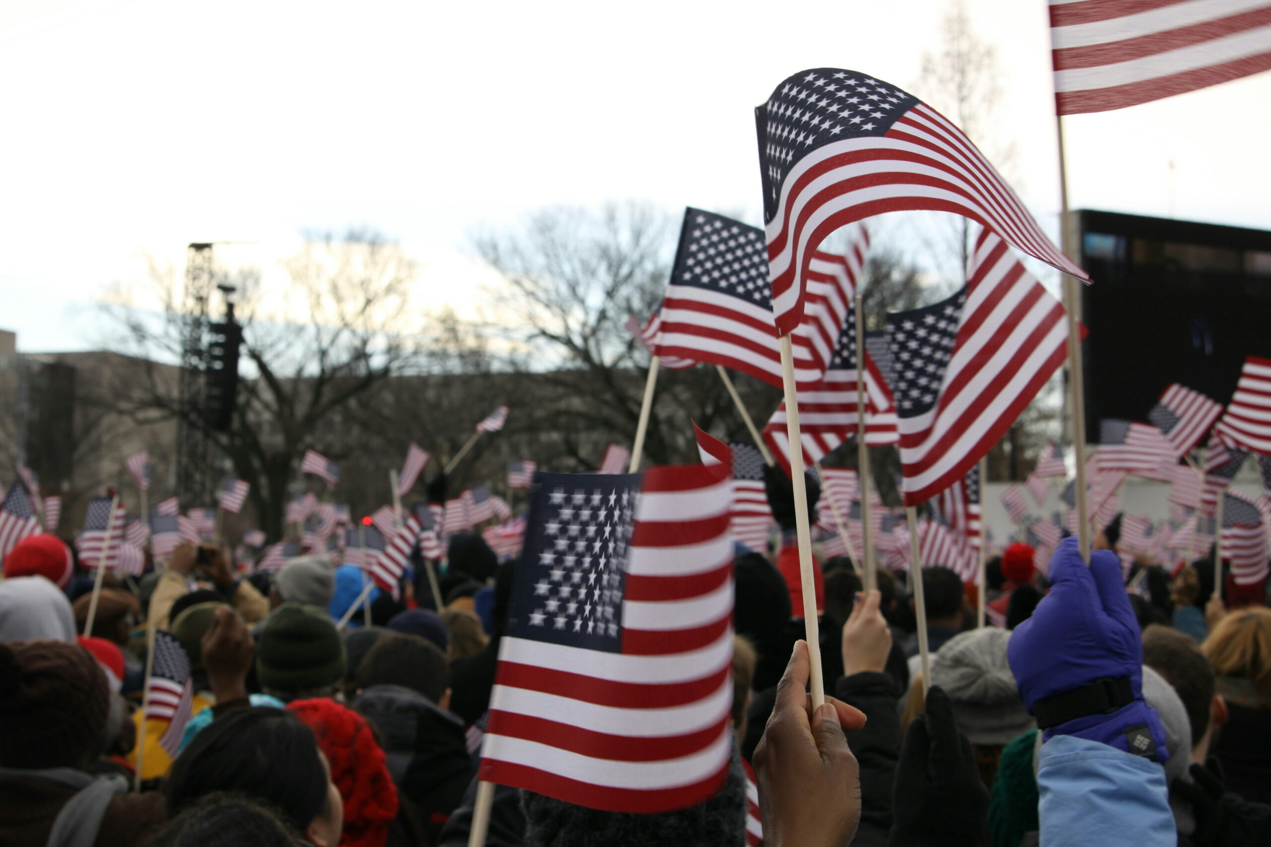 A large crowd of people outdoors waving multiple American flags during an event.