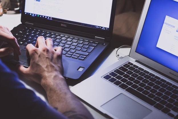 A pair of hands works on two sets of keyboards at a desk.