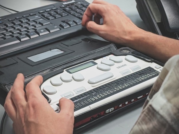 A pair of hands rest on a Braille keyboard.