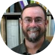 A headshot of a middle aged man with glasses and facial hair, George H. Michaels