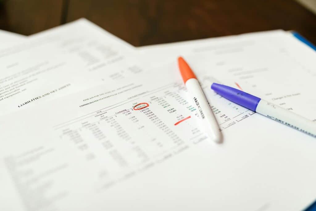 Orange and blue markers rest on sheets of paper containing numbers arranged in tables.