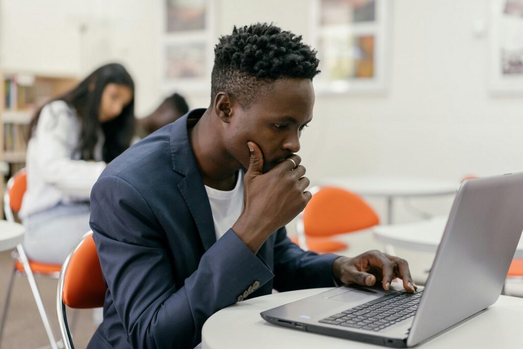 Student wearing a blue blazer and white shirt works on an open laptop