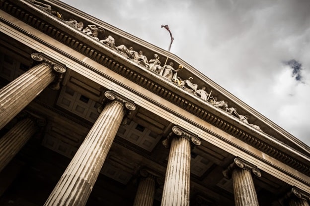 An exterior view of a court building with four tall, gray, marble-ish pillars.