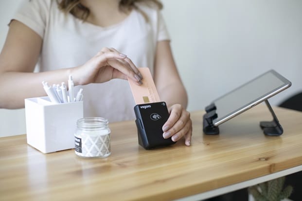 A woman wearing a white shirt places a credit card into a credit card reader