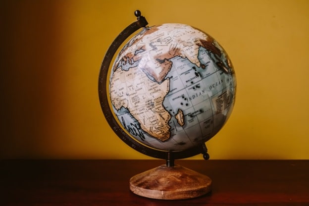 A globe sits on a pedestal against a yellow-ish background