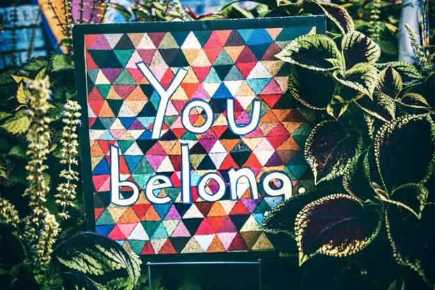 A multicolored sign with the words 'You Belong' written in white