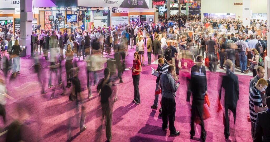 A blurred shot of the NAB show floor with dozens of people walking across the floor