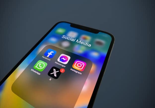 Close up of an iPhone screen showing social media app icons - Facebook, Instagram, Snapchat, and X