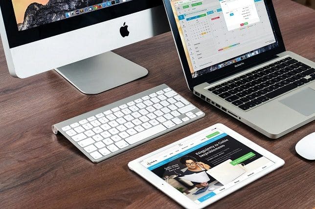 A desktop, laptop, and tablet all sit next to each other on a desk.