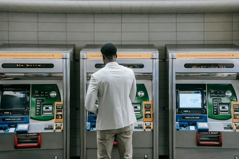 a man stands in front of three ticket purchasing machines in a train station