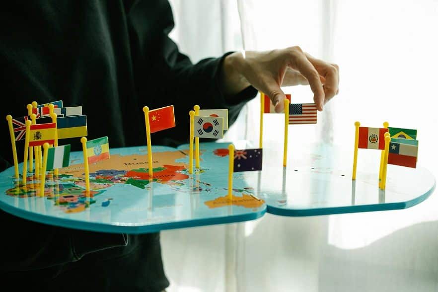 A person arranges country flags on a flat world map.