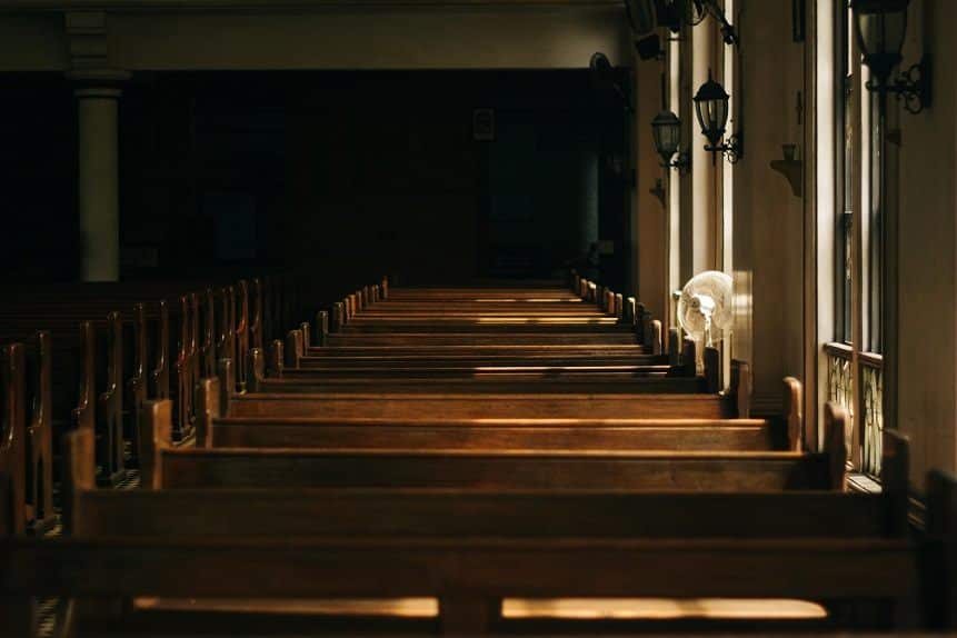 A row of empty pews in a dimly lit house of worship