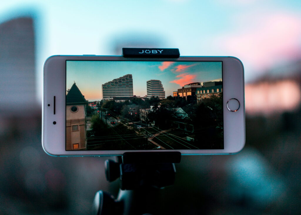 An iPhone is positioned horizontally as a video is displayed of a city scene with a Joby-branded device on the top of it.