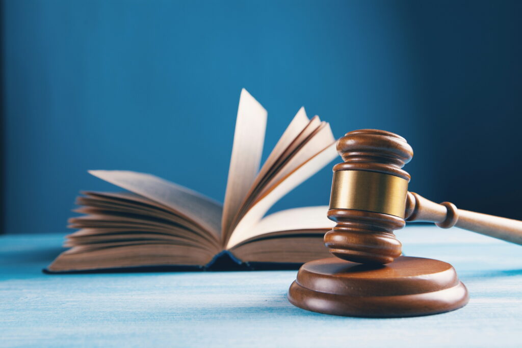 An open book sits on a desk next to a wooden legal gavel