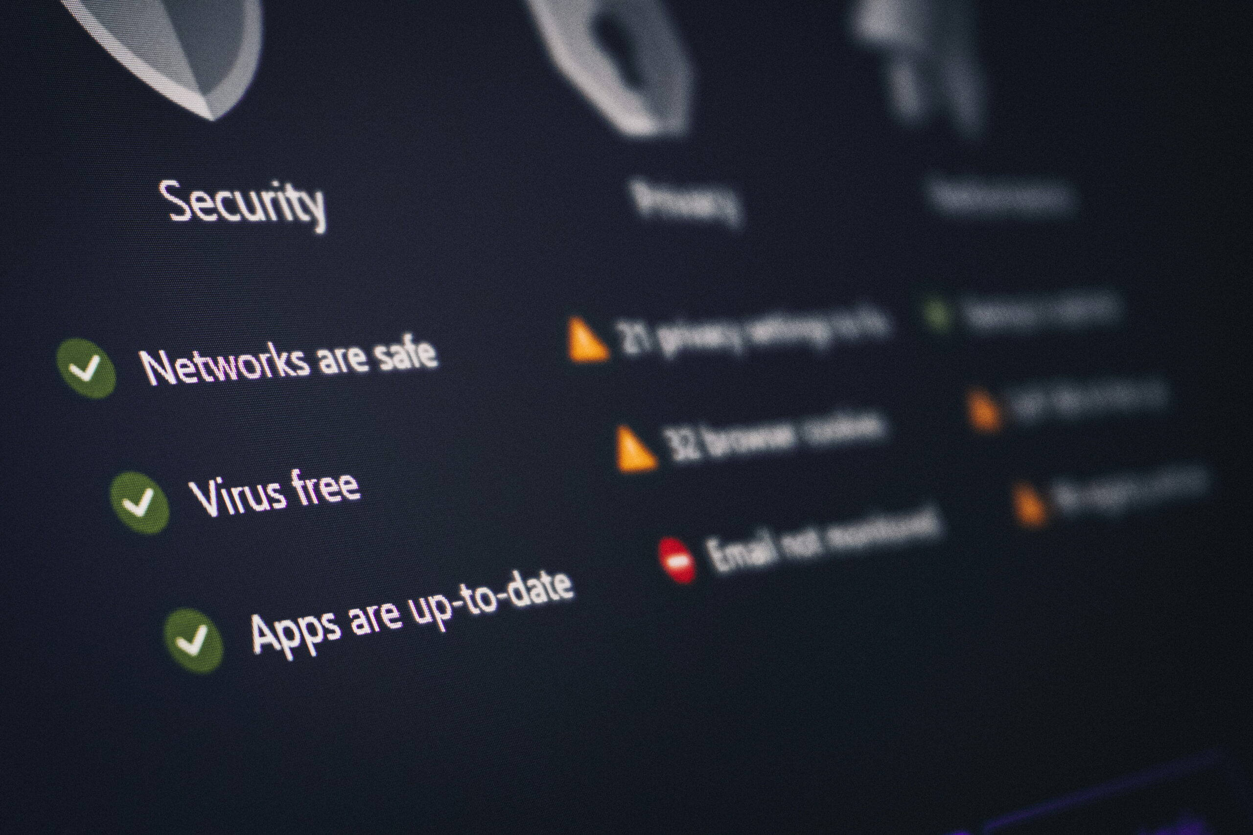 Close-up of a dark digital dashboard showing green checkmarks next to safety statuses including "Networks are safe," "Virus free," and "Apps are up-to-date."