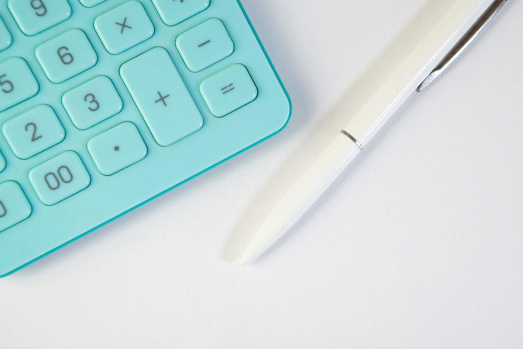 A turquoise calculator is seen on the edge of the screen and a white pen sits next to it