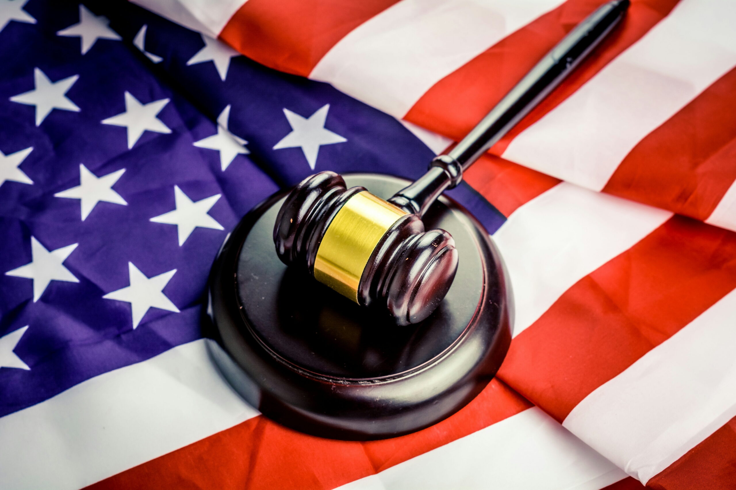 A wooden judge's gavel resting on top of a folded American flag, representing United States law and judicial services.