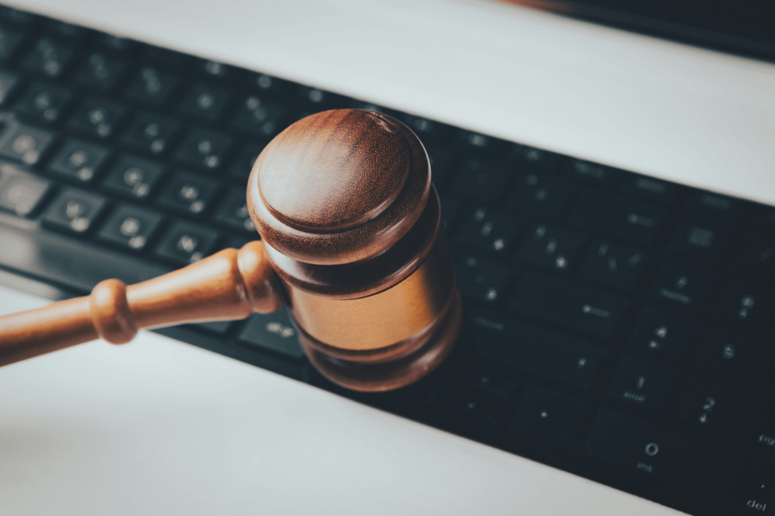 A legal gavel that's brown wooden is shown on top of a black keyboard to denote legal technology